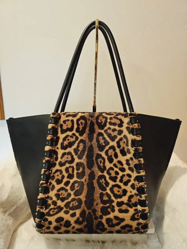 A leopard print bag sitting on top of a bed.