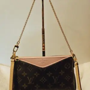 A brown and pink purse hanging on a stand.