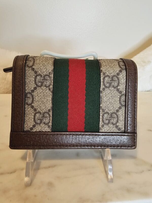 A small wallet with a red, green and white stripe on it.