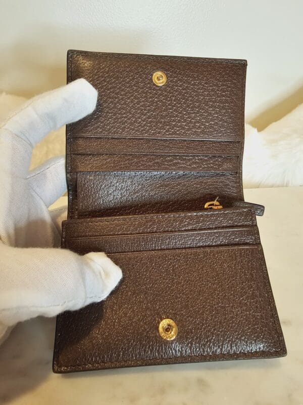 A person holding an open brown wallet.