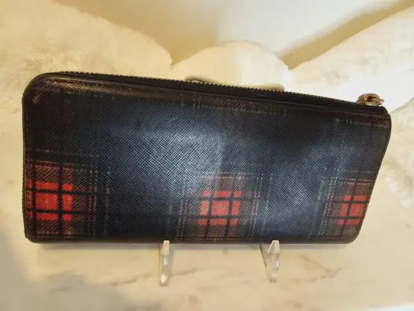 A black and red wallet sitting on top of a table.