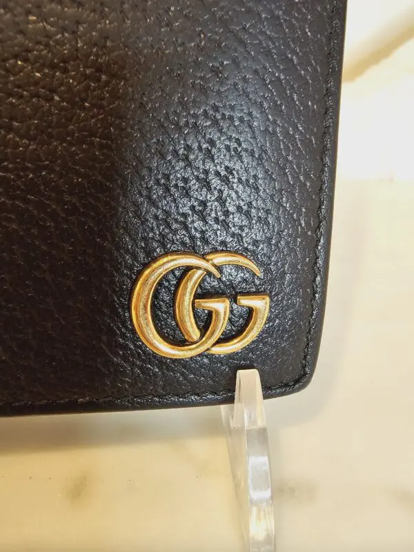 A close up of the gold logo on a black wallet