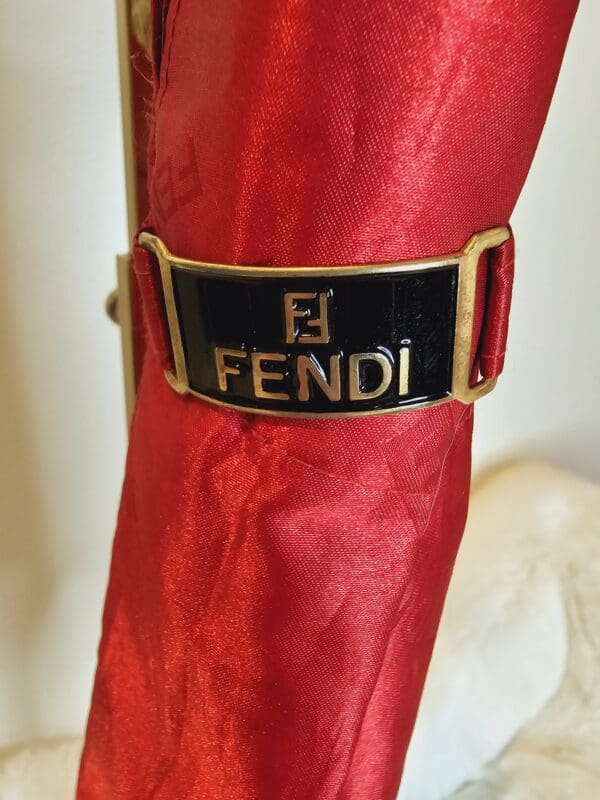 A red umbrella with a black fendi logo on it.