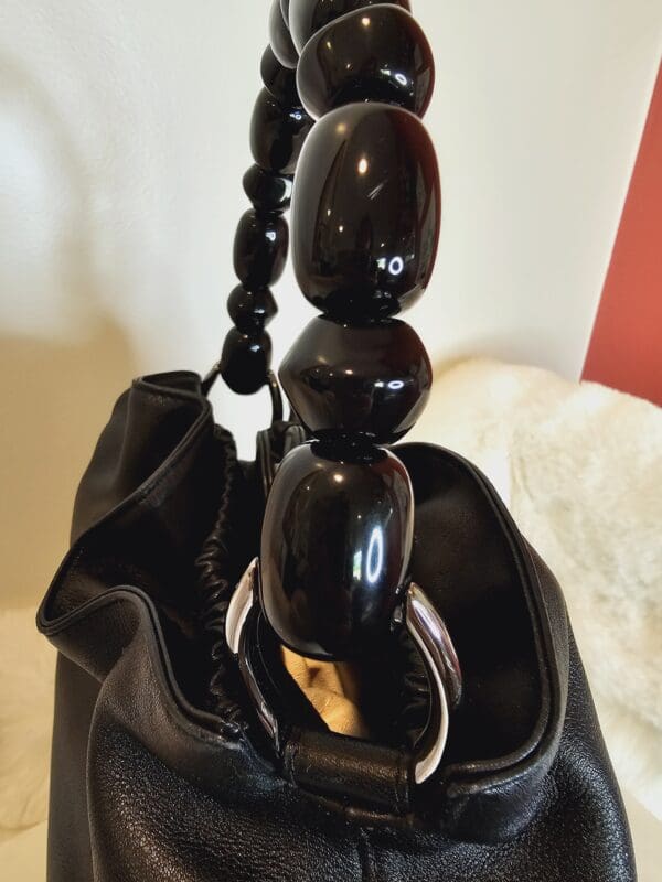 A black purse with a wooden bead and ring on it.