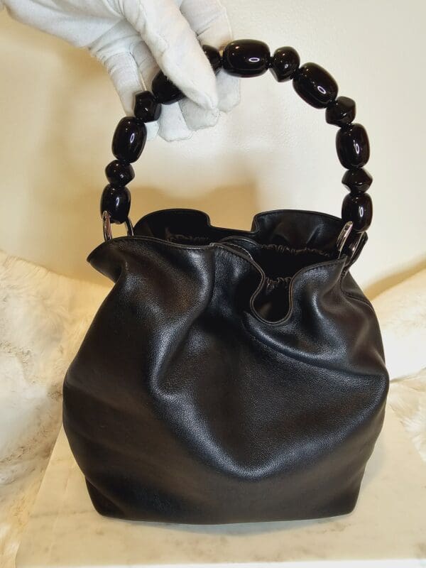 A black purse with wooden handle and chain