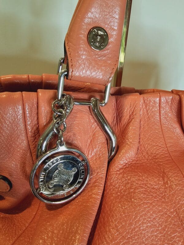 A close up of the purse with a key chain attached.