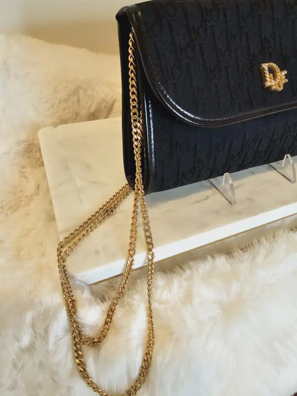 A black purse with gold chain on top of it.