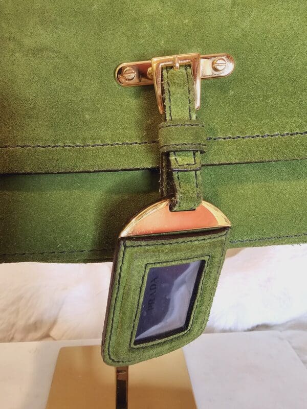 A green purse with a gold clasp and a mirror.