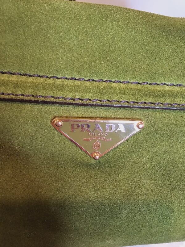 A close up of the prada logo on a green bag