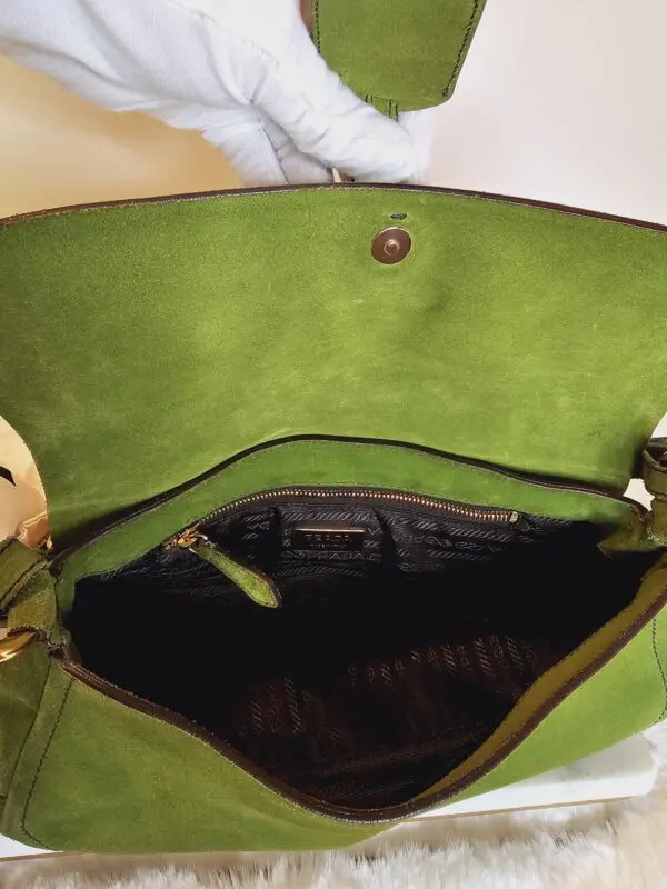 A green purse is open and has a black handle.