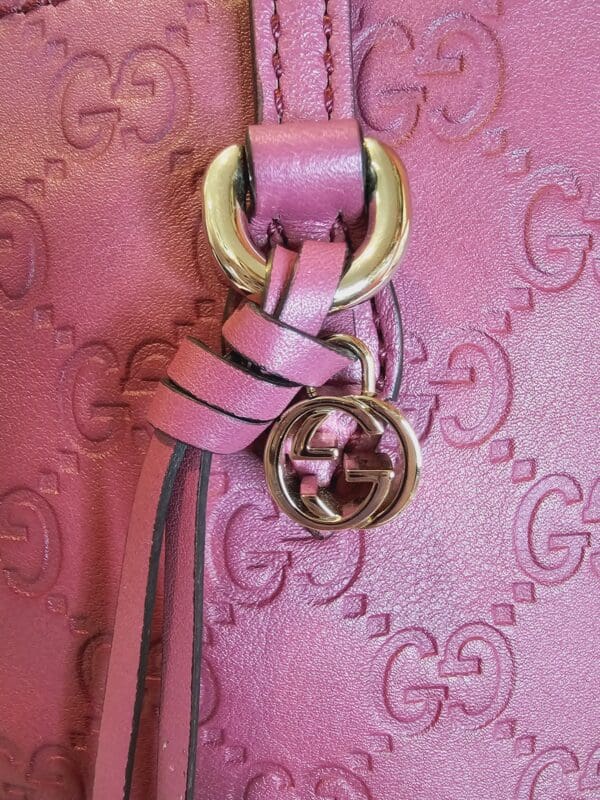 A close up of the handle on a pink purse