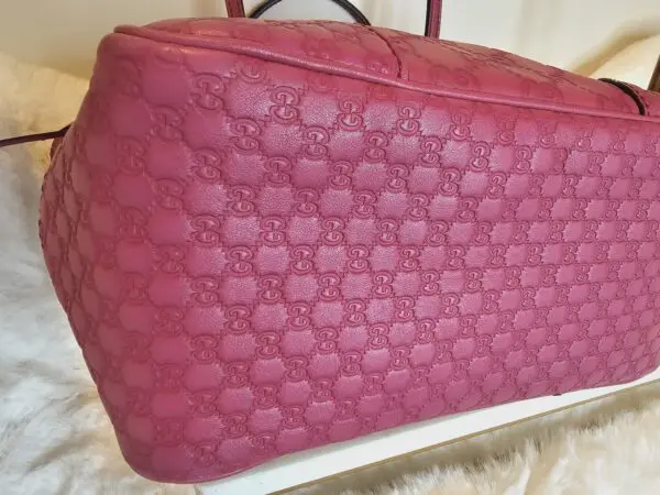 A pink bag sitting on top of a white rug.