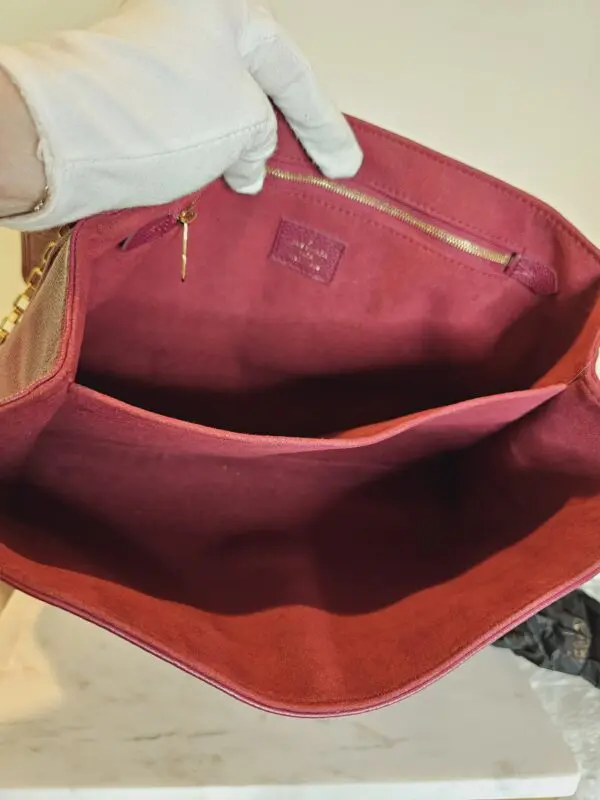 A person holding onto the inside of a red purse.