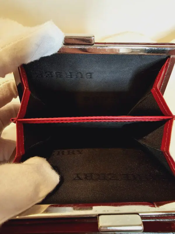 A person holding an open wallet with two cards inside.