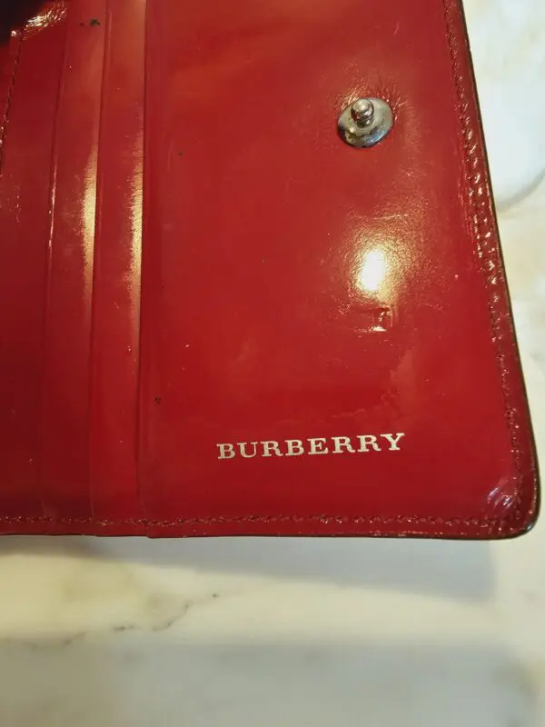 A close up of the burberry logo on a red wallet