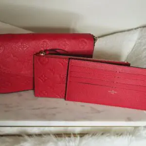 Three red wallets sitting on a table.