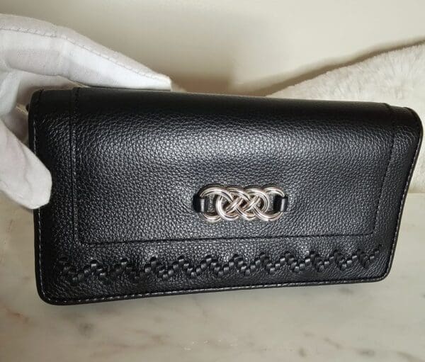 A black purse is shown with a white glove.