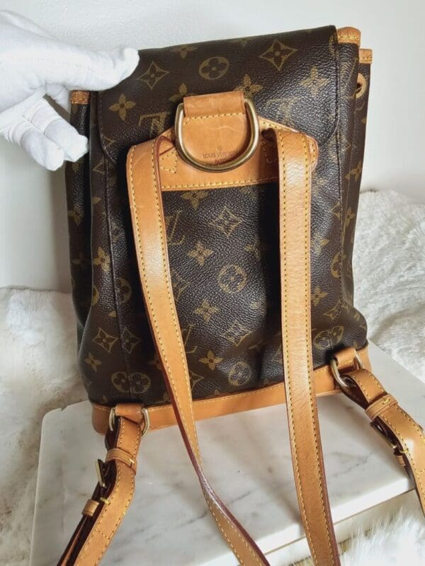 A brown and tan backpack sitting on top of a bed.