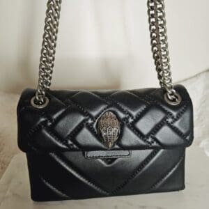 A black purse with silver chain and a metal skull on it.