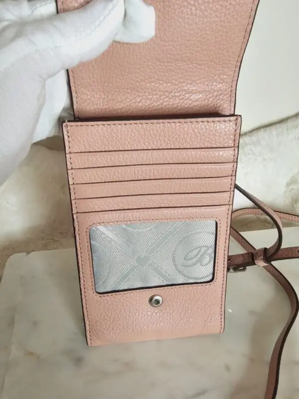 A pink wallet sitting on top of a table.