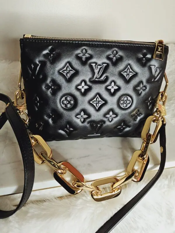 A black purse with gold chain and lock.