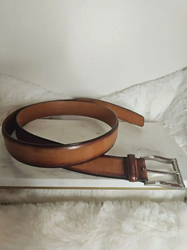 A brown belt sitting on top of a white box.