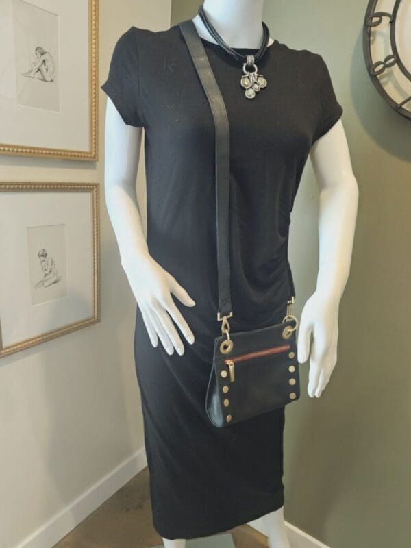 A mannequin wearing a black dress and holding a purse.