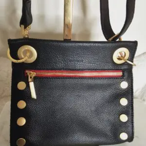 A black purse with gold rivets and red lining.