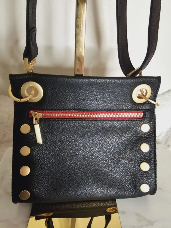 A black purse with gold rivets and red lining.