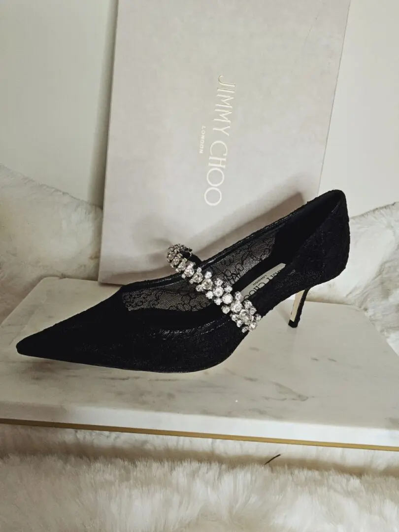 A black shoe with a diamond strap on it's side.