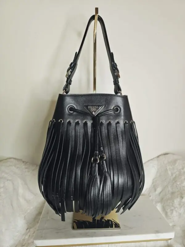 A black bag with fringes hanging on the wall