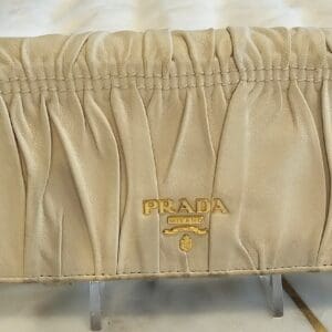 A beige bed skirt with a gold prada logo.