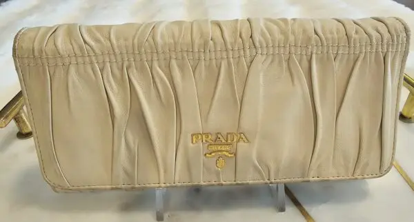 A beige bed skirt with a gold prada logo.