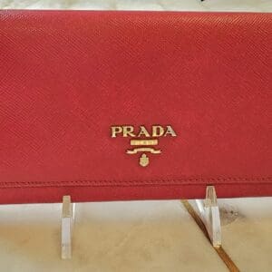 A red prada wallet sitting on top of a table.