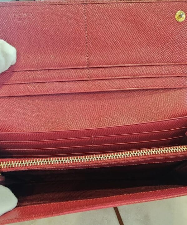 A red purse is open and has two hands on the bottom of it.