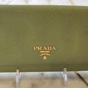 A green prada wallet sitting on top of a table.