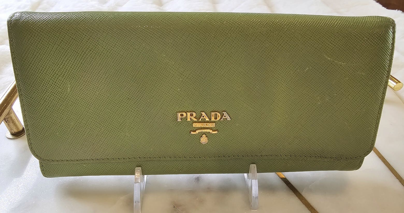 A green prada wallet sitting on top of a table.