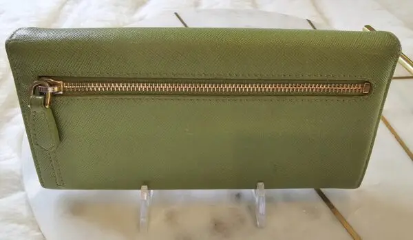 A green purse with a gold zipper on top of it.