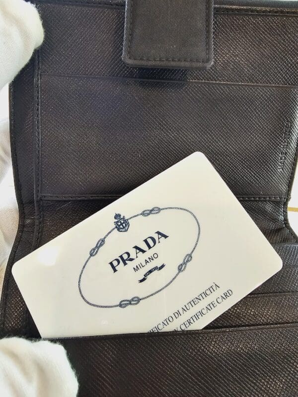 A prada card sitting in the middle of a purse.