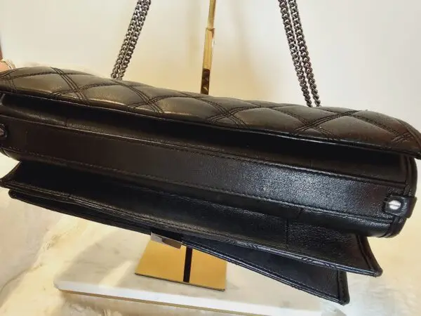 A close up of the chain strap on a black purse