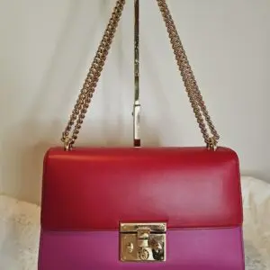 A red and purple purse hanging on a wall.