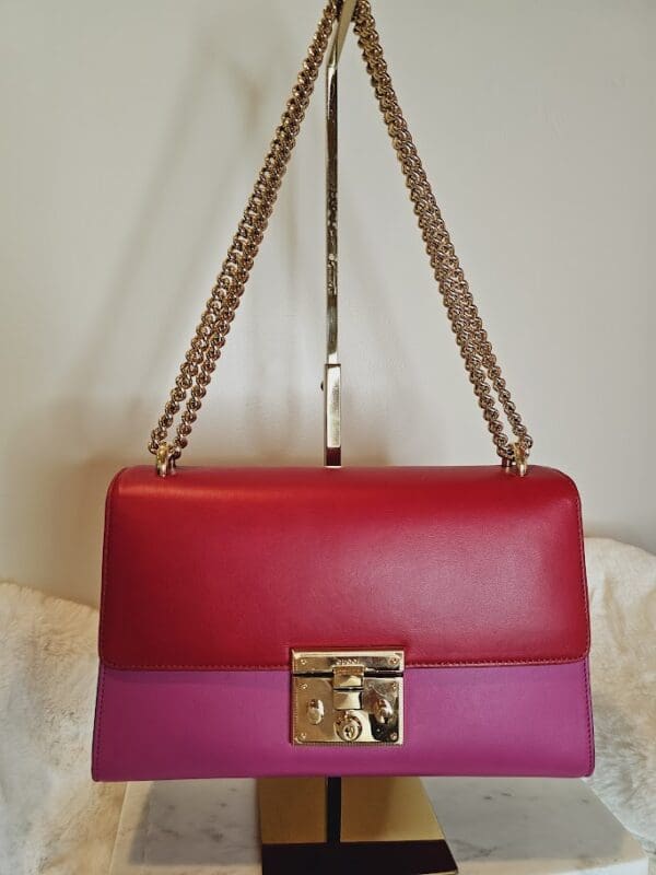 A red and purple purse hanging on a wall.