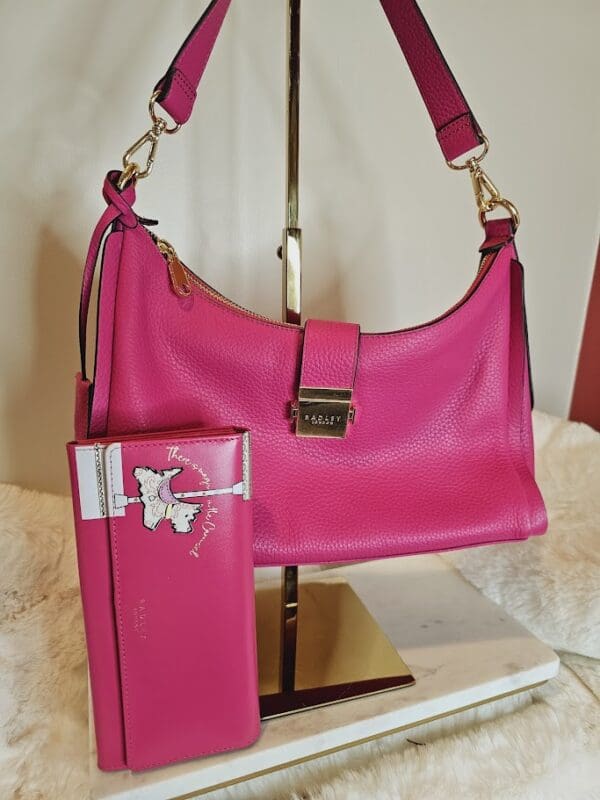 A pink purse and wallet on display in a room.