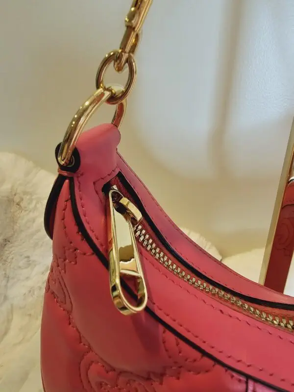 A pink purse with gold hardware and a mirror