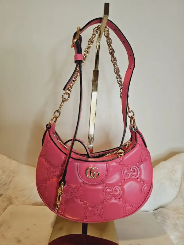 A pink purse is hanging on the wall.