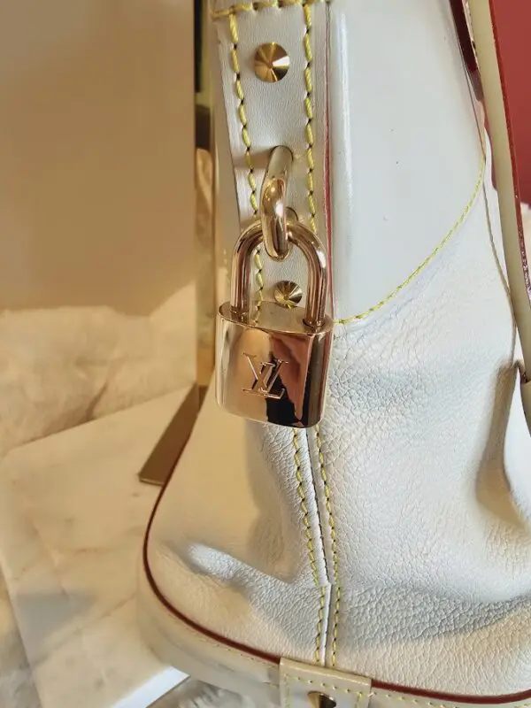 A close up of the lock on a white purse