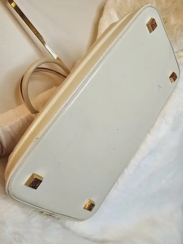 A white purse sitting on top of a bed.