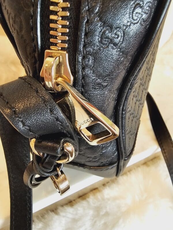 A close up of the zipper on a black purse