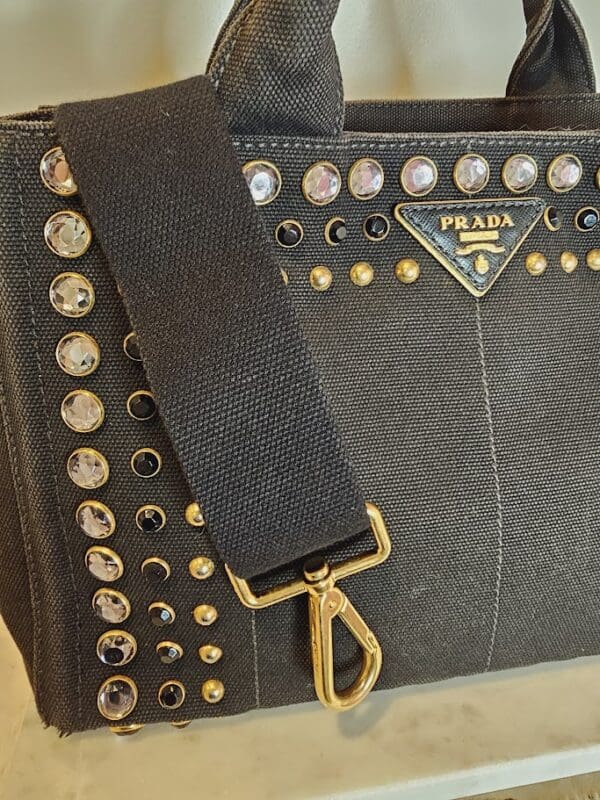 A black purse with gold and silver studs on it.