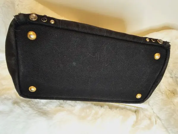 A black purse sitting on top of a white blanket.